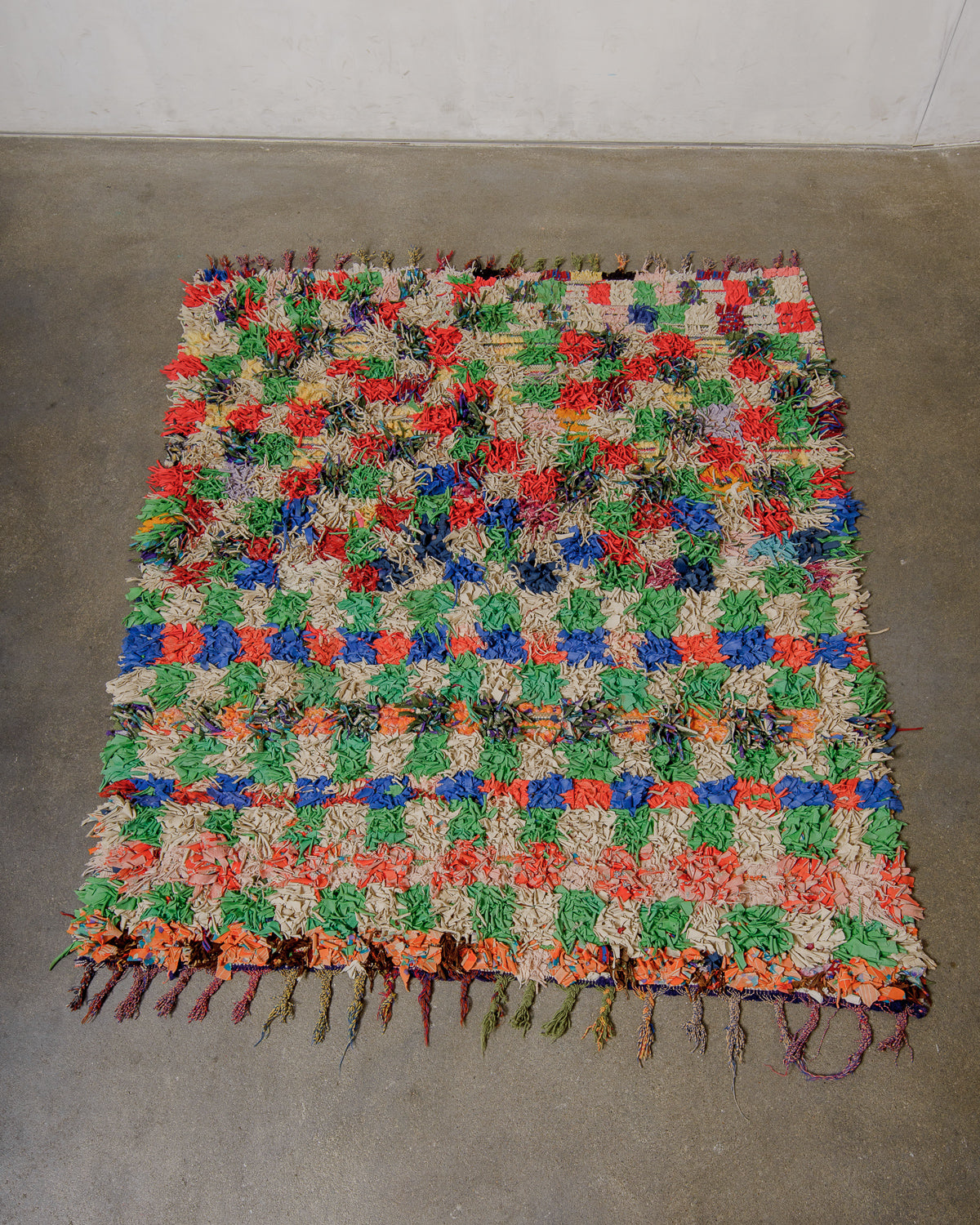Multicolorued woven rug on a concrete floor